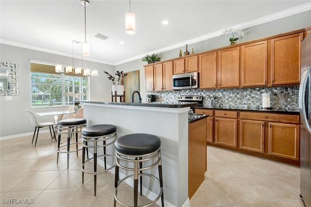 kitchen with light tile patterned floors, visible vents, appliances with stainless steel finishes, a kitchen island with sink, and pendant lighting