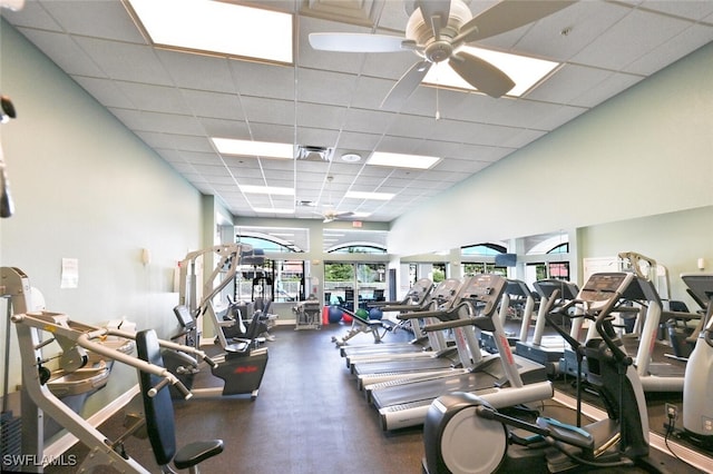 exercise room featuring ceiling fan, a drop ceiling, a towering ceiling, and visible vents