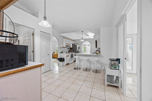 kitchen featuring light tile patterned flooring, hanging light fixtures, a breakfast bar, white range with electric cooktop, and vaulted ceiling