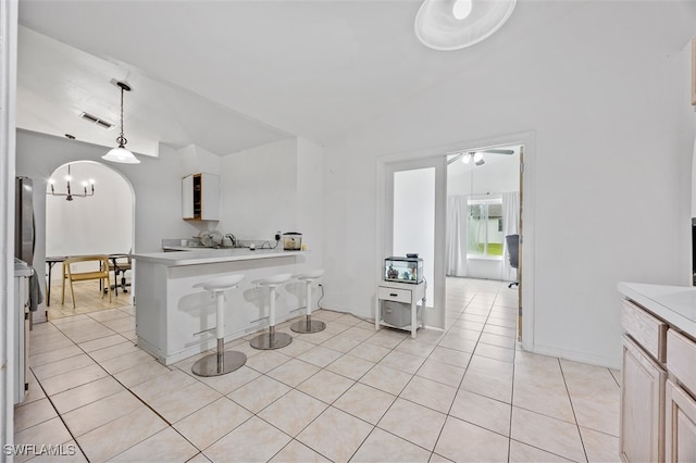 kitchen with lofted ceiling, light tile patterned flooring, a breakfast bar area, and pendant lighting