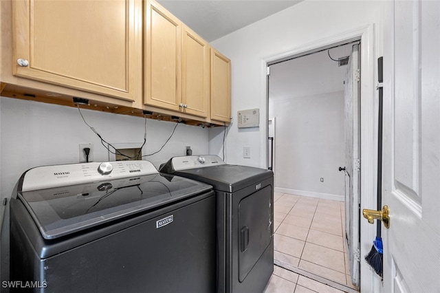 laundry area with independent washer and dryer, light tile patterned floors, and cabinets