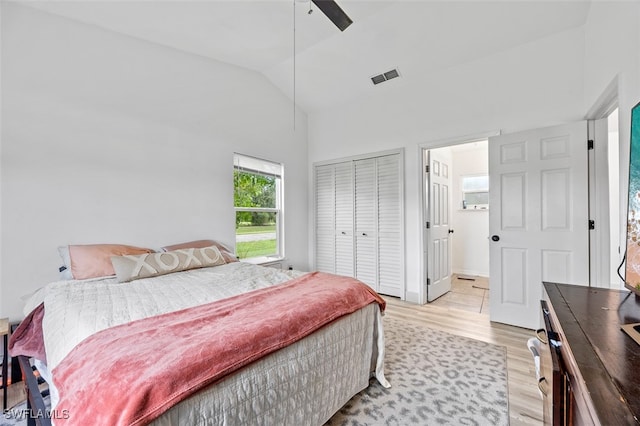 bedroom featuring ceiling fan, light hardwood / wood-style floors, lofted ceiling, and a closet