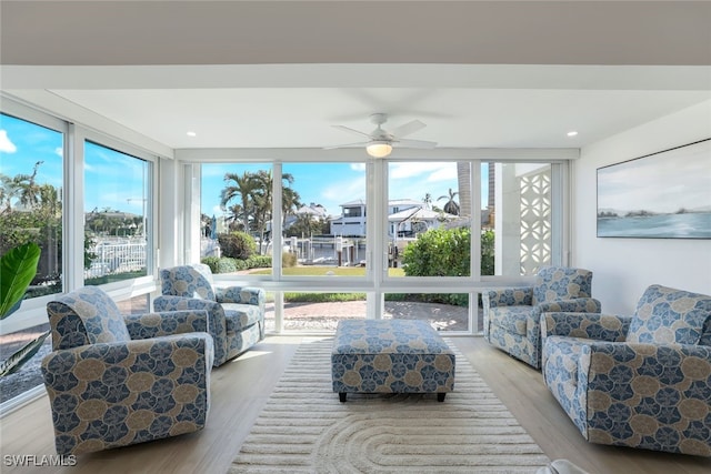 sunroom with light hardwood / wood-style flooring, ceiling fan, and a wall of windows