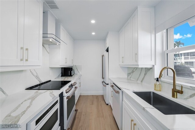 kitchen with white cabinetry, sink, white appliances, and wall chimney exhaust hood