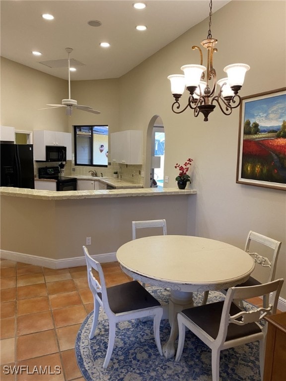 tiled dining room with ceiling fan with notable chandelier and sink