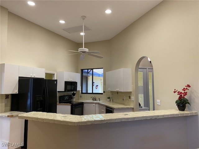 kitchen featuring decorative backsplash, white cabinets, kitchen peninsula, black appliances, and ceiling fan