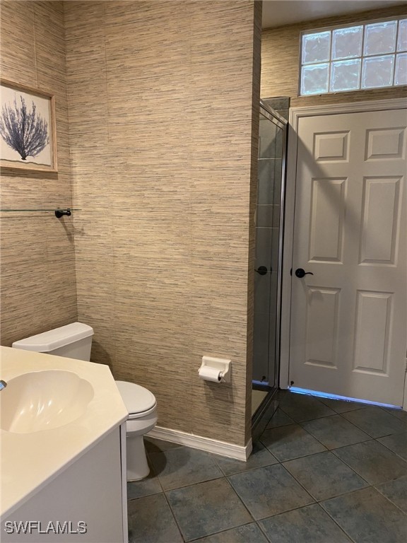 bathroom featuring walk in shower, vanity, toilet, and tile patterned floors