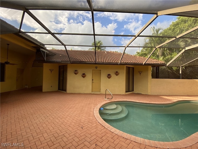 view of swimming pool featuring ceiling fan, glass enclosure, and a patio