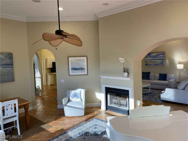 tiled living room with ceiling fan and crown molding