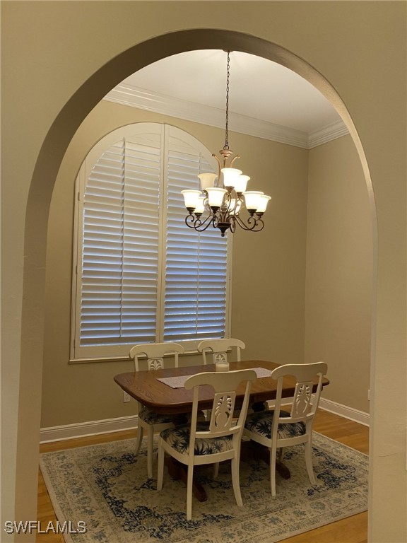 dining area featuring an inviting chandelier, hardwood / wood-style flooring, and crown molding