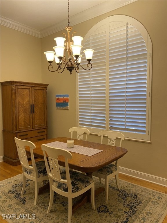 dining space with light hardwood / wood-style floors, ornamental molding, and a notable chandelier