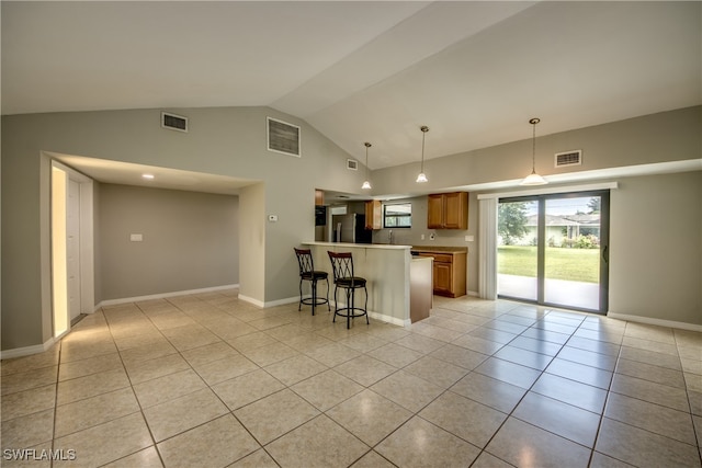 kitchen with light tile patterned floors, a breakfast bar area, hanging light fixtures, stainless steel fridge with ice dispenser, and kitchen peninsula