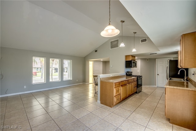 kitchen featuring sink, decorative light fixtures, vaulted ceiling, light tile patterned floors, and stainless steel appliances