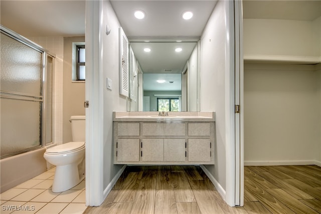 full bathroom with vanity, hardwood / wood-style floors, toilet, and combined bath / shower with glass door