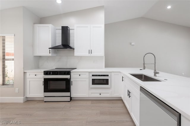 kitchen with sink, wall chimney exhaust hood, light hardwood / wood-style flooring, vaulted ceiling, and white appliances