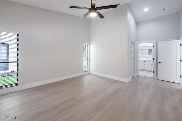 spare room with light wood-type flooring, high vaulted ceiling, and ceiling fan