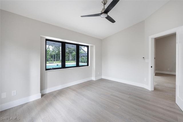 empty room with ceiling fan, light hardwood / wood-style floors, and vaulted ceiling