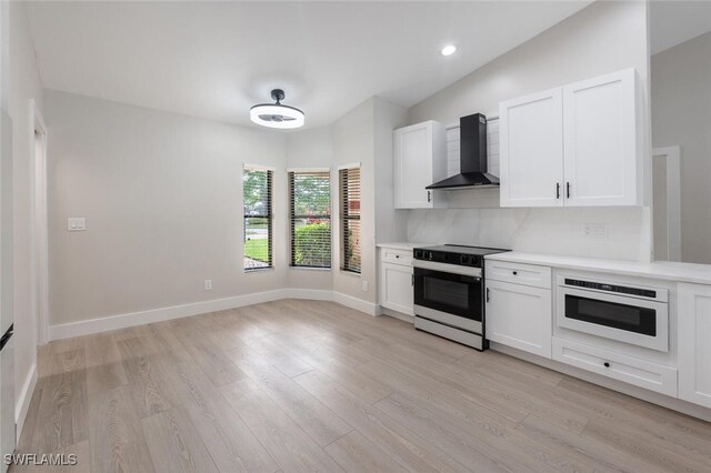 kitchen featuring oven, white cabinetry, stainless steel electric range oven, and wall chimney range hood