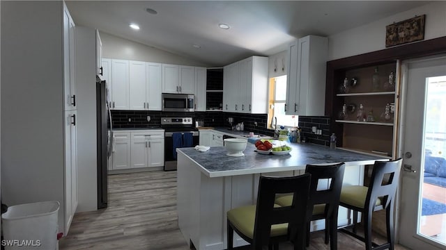 kitchen with backsplash, a peninsula, appliances with stainless steel finishes, and plenty of natural light
