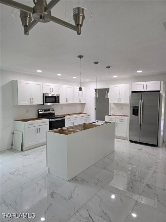 kitchen featuring hanging light fixtures, stainless steel appliances, a center island, and white cabinets