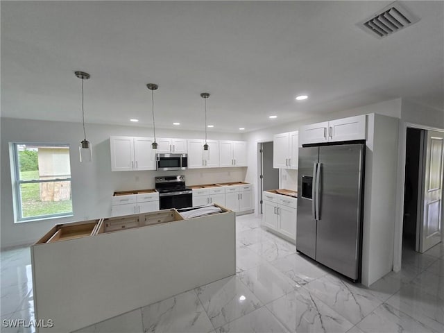 kitchen with pendant lighting, stainless steel appliances, a kitchen island, and white cabinets