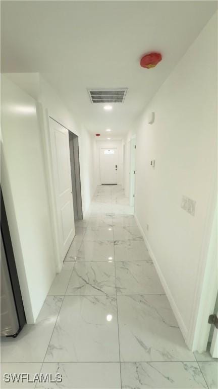 hallway featuring baseboards, visible vents, and marble finish floor