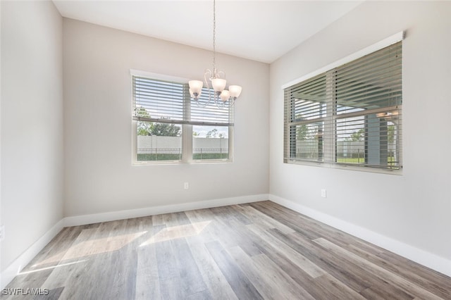 spare room with a chandelier and wood-type flooring