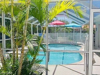 view of pool with glass enclosure and a patio