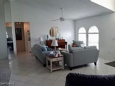 living room with high vaulted ceiling, ceiling fan, light tile patterned floors, and a textured ceiling