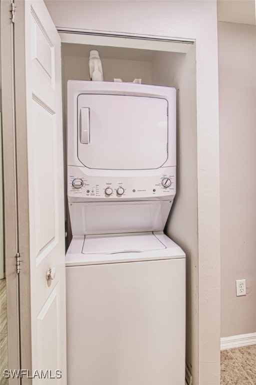 clothes washing area featuring light tile patterned flooring and stacked washer and dryer