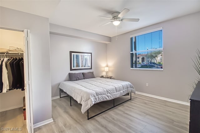 bedroom with a closet, light hardwood / wood-style floors, a walk in closet, and ceiling fan