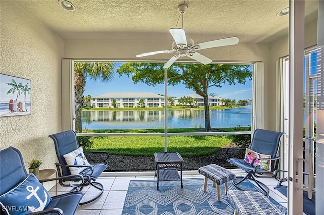 sunroom / solarium featuring ceiling fan, a water view, and a healthy amount of sunlight