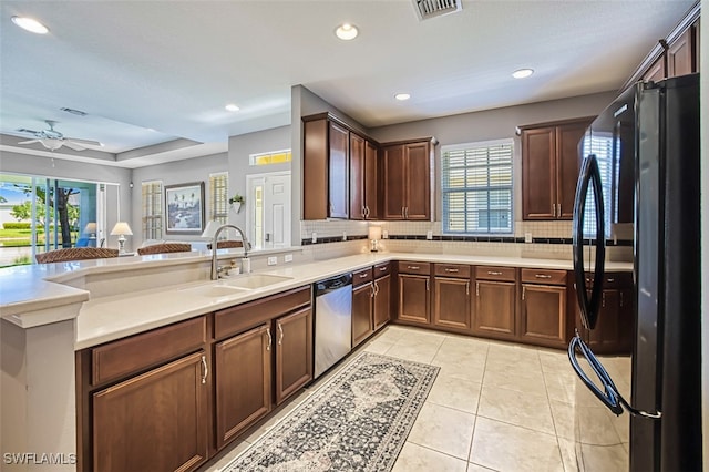 kitchen with light tile patterned flooring, sink, dishwasher, black refrigerator, and decorative backsplash