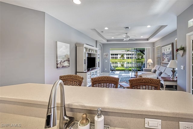 kitchen featuring a raised ceiling and ceiling fan