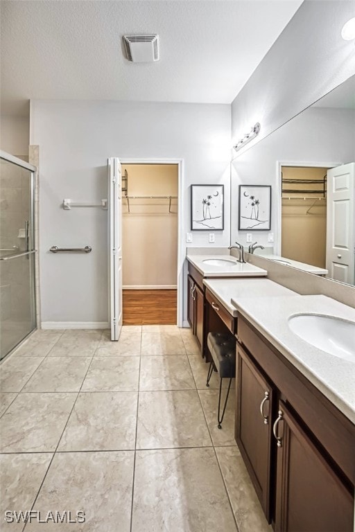 bathroom with walk in shower, vanity, tile patterned flooring, and a textured ceiling