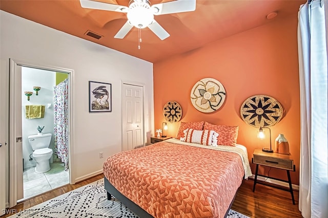 bedroom with ensuite bath, ceiling fan, and dark hardwood / wood-style flooring