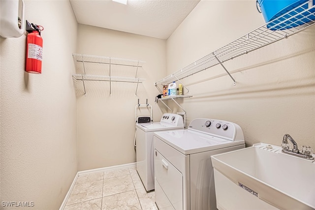 clothes washing area featuring light tile patterned floors, separate washer and dryer, a textured ceiling, and sink