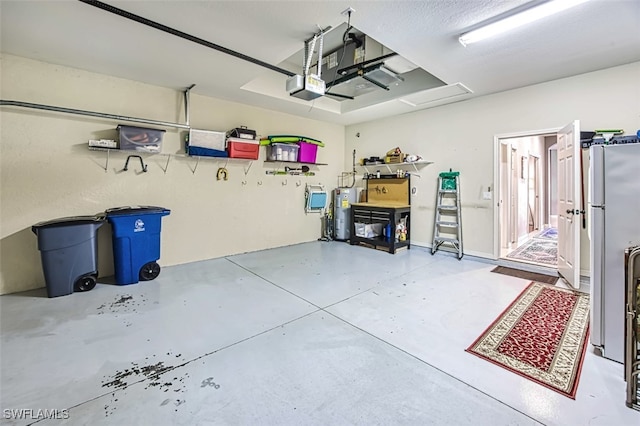 garage featuring a garage door opener, electric water heater, and white refrigerator