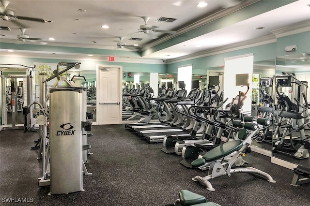 exercise room featuring ceiling fan, a tray ceiling, and ornamental molding