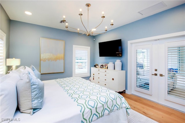 bedroom with a chandelier, access to exterior, and hardwood / wood-style floors