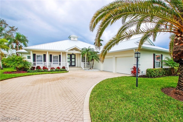 view of front of home featuring a front lawn, covered porch, and a garage