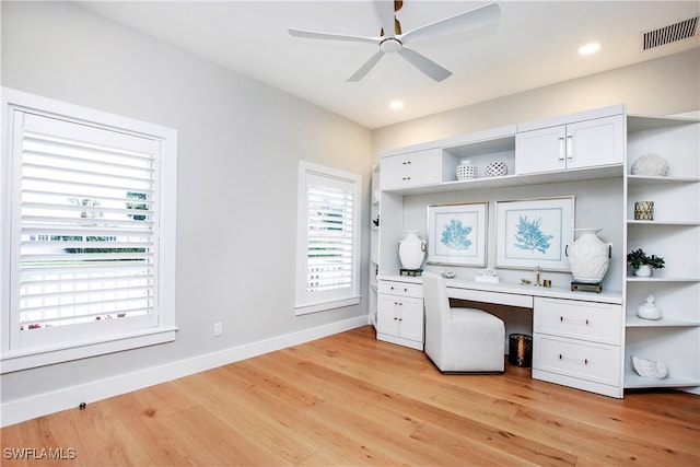 office space featuring built in desk, light wood-type flooring, and ceiling fan