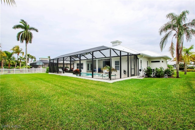 rear view of property with a yard, a fenced in pool, glass enclosure, and a patio