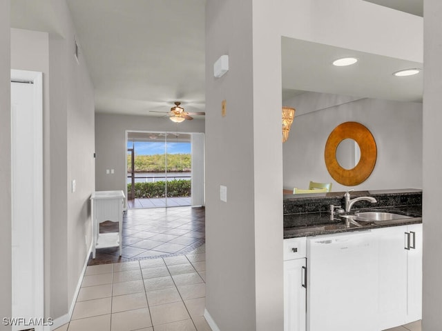 kitchen with dark stone countertops, white cabinetry, light tile patterned floors, ceiling fan, and sink