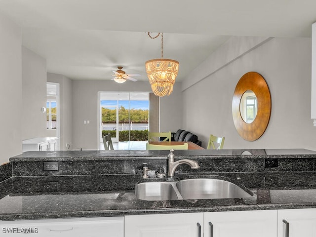 kitchen with ceiling fan, sink, decorative light fixtures, white cabinetry, and dark stone countertops