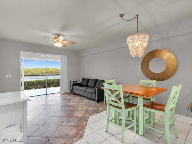 dining space with ceiling fan with notable chandelier and light tile patterned floors