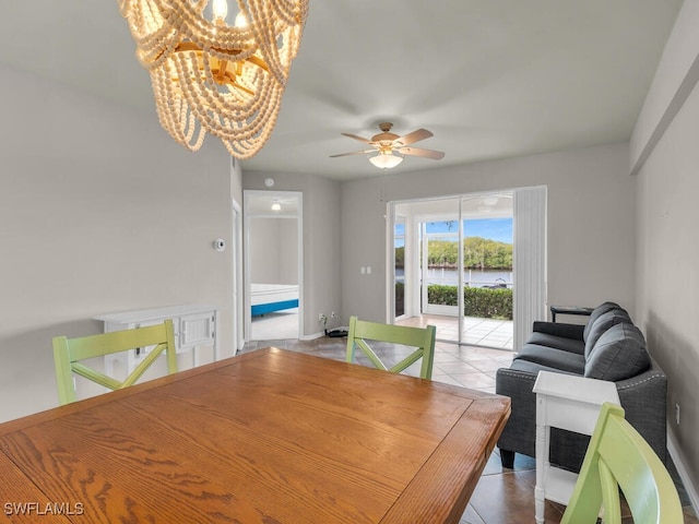 tiled dining area featuring ceiling fan with notable chandelier