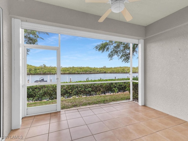 unfurnished sunroom with a water view and ceiling fan