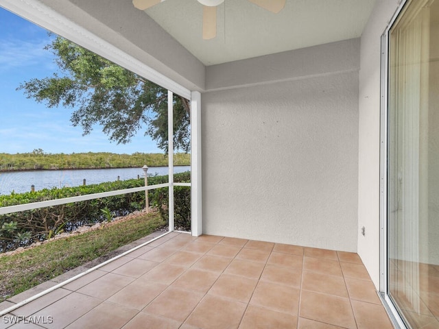 unfurnished sunroom featuring a water view and ceiling fan