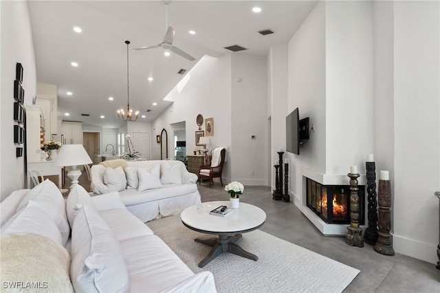 living room featuring high vaulted ceiling, a multi sided fireplace, and ceiling fan with notable chandelier